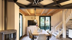 A modern dining area with a wooden table and chairs, a fireplace, and a staircase. - Olivia s Home in Ponte di Legno (Ponte di Legno)