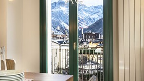 A dining area with a view of a mountain town through a glass door. - Olivia s Home in Ponte di Legno (Ponte di Legno)