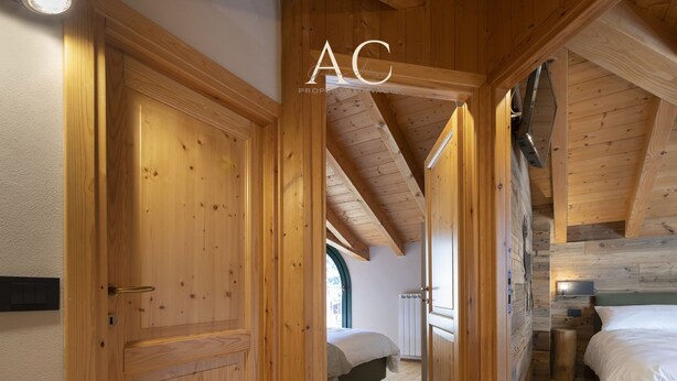 A wooden interior with a loft bedroom, a wooden door, and a bed with white bedding. - Olivia s Home in Ponte di Legno (Ponte di Legno)