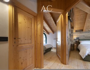 Un intérieur en bois avec une chambre en mezzanine, une porte en bois et un lit avec une literie blanche.