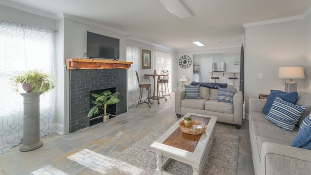 A living room with a fireplace, a sofa, a coffee table, and a dining area with a table and chairs.