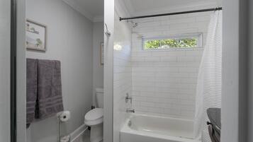 Un baño con bañera, inodoro y ventana.