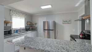 A modern kitchen with granite countertops, stainless steel appliances, and white cabinetry.
