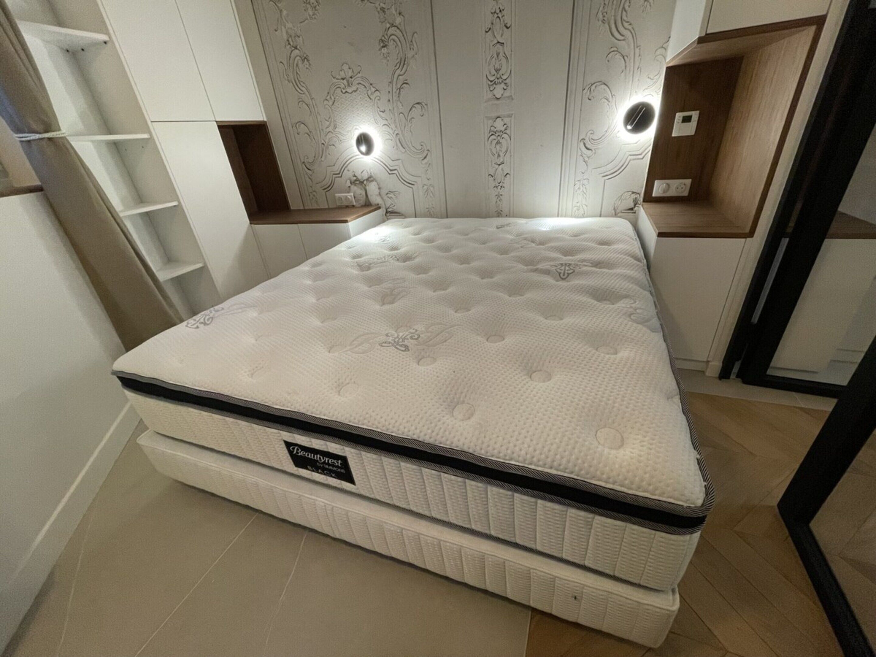 A double bed with a white mattress and a label reading "Beautyrest."