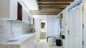 A modern kitchen with marble countertops, wooden beams, and a central island. - Superb Apartment Place des Vosges Le Marais (Paris)