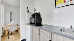 Una cocina moderna con microondas integrado, un lavamanos y una zona de comedor con sillas y una mesa.