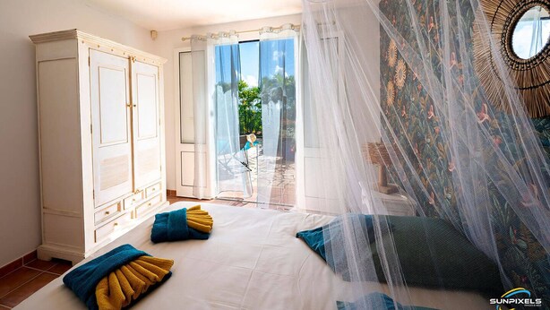 Une chambre avec un grand lit, une armoire et une vue sur l’extérieur.