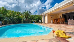Une piscine avec un espace patio, du mobilier d’extérieur et une vue sur le ciel.