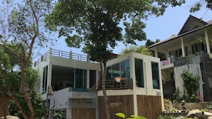 A modern two-story building with large windows, a balcony, and a wooden fence.
