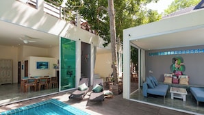 A modern house with a swimming pool, a dining area, and a living room with a mural.