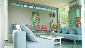 A living room with a blue sofa, a white coffee table, and a mural on the wall.