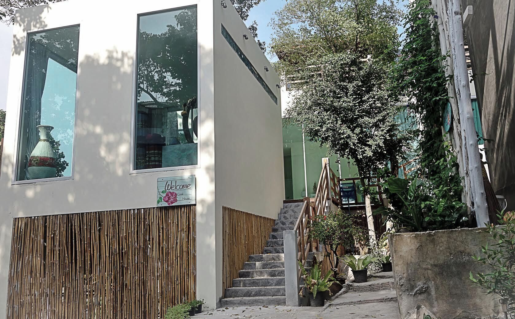Un edificio con un cartel que dice 'Welcome', una escalera y una pared de bambú.