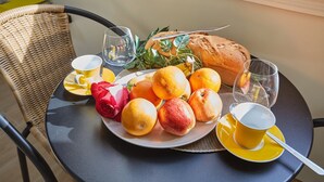 A round table with a plate of fruit, a loaf of bread, and a glass of water.
