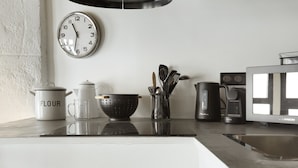 Un ripiano da cucina con una tazza bianca etichettata "FLOUR", un colino, un bollitore e un forno a microonde.