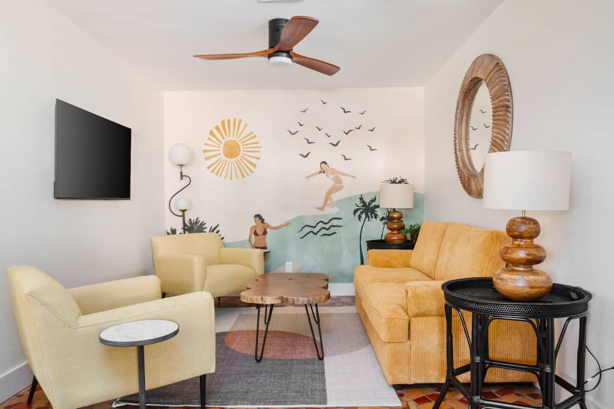 Una sala de estar con sofá, sillón, mesa de centro y ventilador de techo.