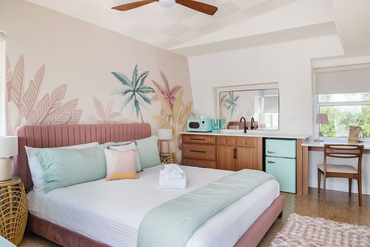 Un dormitorio con cama, escritorio, silla, microondas y refrigerador pequeño.