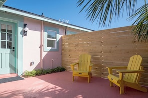 A house with a pink exterior, a wooden fence, and two yellow Adirondack chairs outside. - Haleys Court Boutique Motel (St. Augustine)
