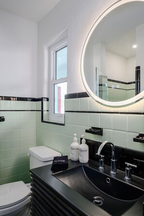 A modern bathroom with a black sink, a round mirror, and a toilet. - Haleys Court Boutique Motel (St. Augustine)