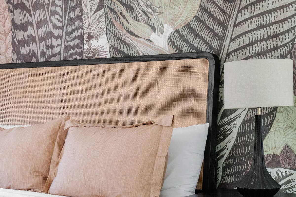 Un dormitorio con cama, mesita de noche y pared decorada con un diseño de hojas.