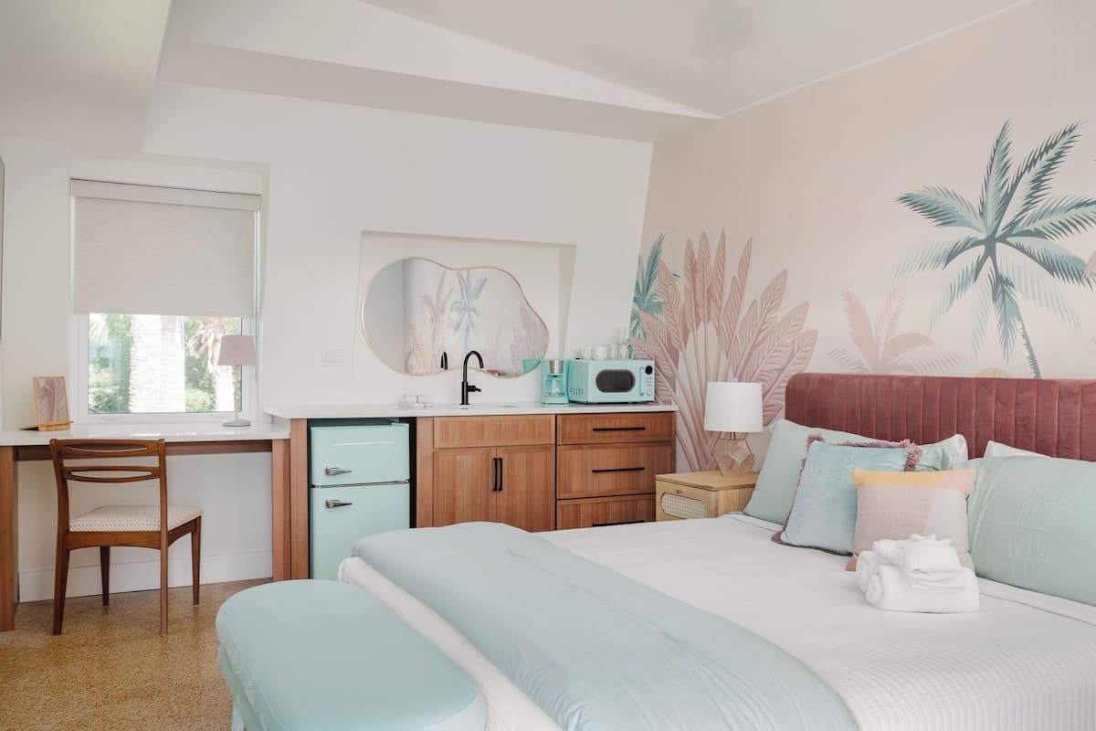 Un dormitorio con cama, escritorio, silla, cómoda y microondas.
