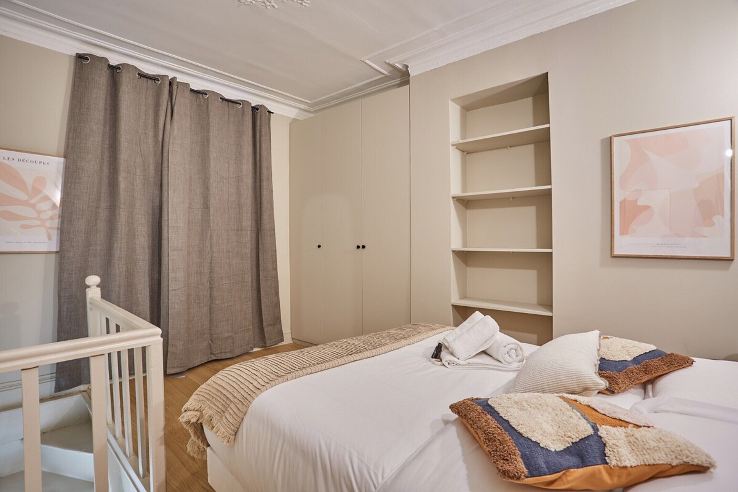 Una camera d'albergo con un letto, un armadio, una scaffalatura e una scala.