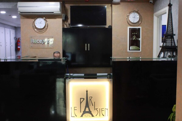 A reception area with a sign reading "Réception," a clock, and a framed poster of the Eiffel Tower. - Le Parisien Tunis (Tunis)