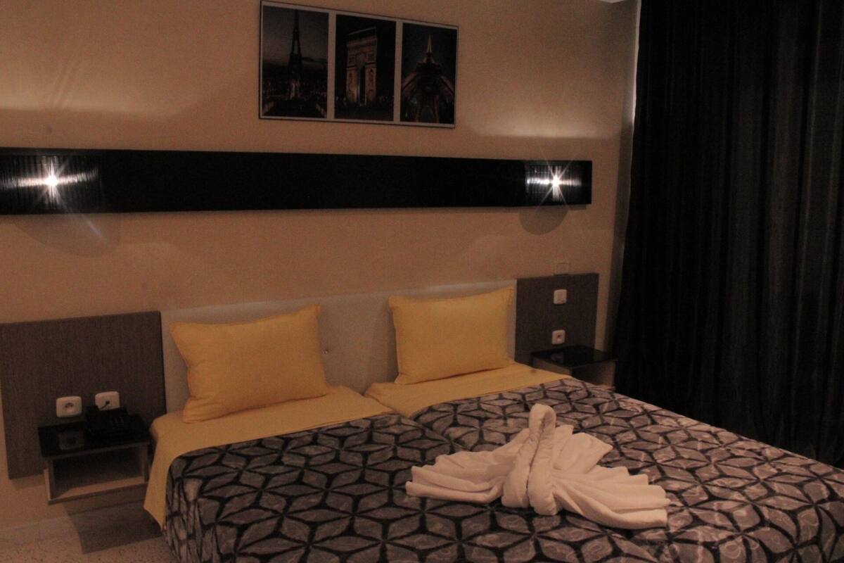 Ein Hotelzimmer mit einem Bett, zwei Nachttischen, einer Kopfteil und einem Wandbild.
