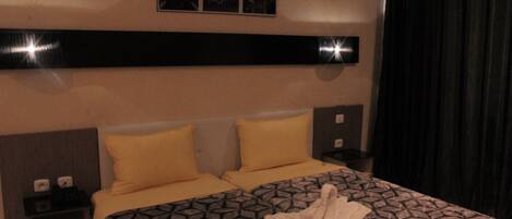 Habitación de hotel con cama, dos mesitas de noche, cabecera y un cuadro colgado en la pared.