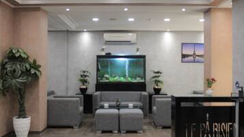 A lobby with a large aquarium, grey sofas, and a reception desk.