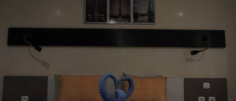 Habitación de hotel con cama, cabecera, cuadro en la pared y almohada.