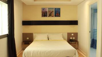 Habitació d'hotel amb un llit gran, un capçal, taules de nit i una televisió penjada a la paret.