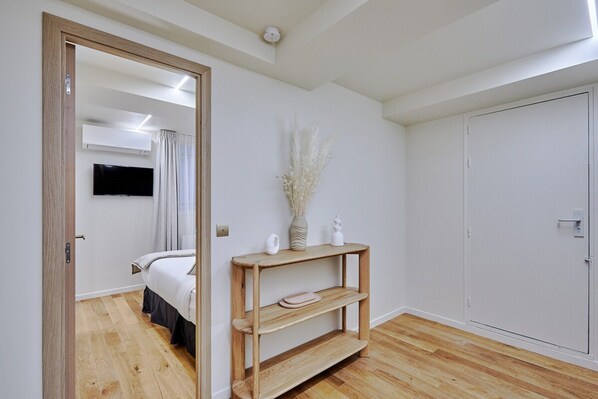 A bedroom with a wooden floor, a bed, a bedside table with a vase, and a wardrobe.