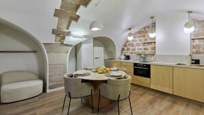 A modern kitchen with a round dining table, two chairs, and a built-in oven. - Superb New Apartement Le Marais Place des Vosges (Paris)