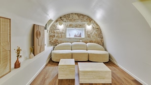 A cozy room with a stone arch, a sofa, and a wooden coffee table. - Superb New Apartement Le Marais Place des Vosges (Paris)