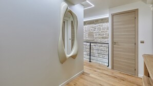 A modern interior with a stone wall, a wooden door, and a unique wall-mounted mirror. - Superb New Apartement Le Marais Place des Vosges (Paris)