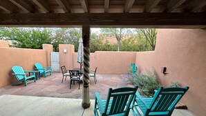 A covered patio with turquoise Adirondack chairs, a table, and a cactus. - Casa Feliz is waiting for you!
 (El Prado)