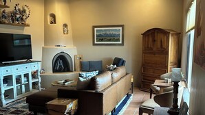 A cozy living room with a fireplace, a sofa, a television, and a dining area. - Casa Feliz is waiting for you!
 (El Prado)