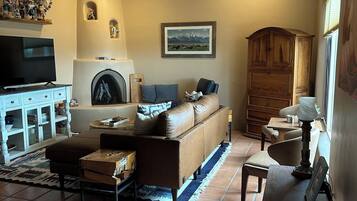 A cozy living room with a fireplace, a sofa, a television, and a dining area.