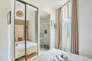 A modern hotel room with a large bed, a glass shower enclosure, and a view of the outdoors. - Superb Apartment Le Marais (Paris)