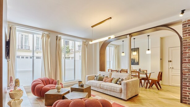 Amplia sala de estar con sofá, sillones y comedor con mesa y sillas.