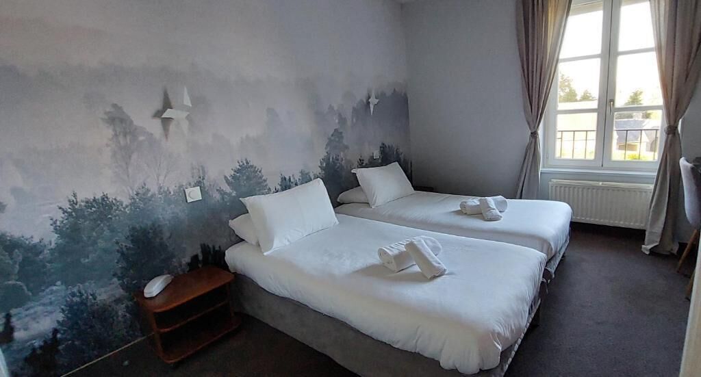 A hotel room with two beds, a nightstand, and a window with curtains.