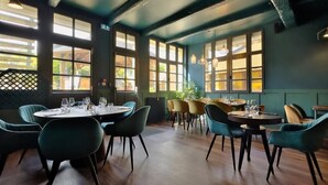 Un ristorante con tavoli e sedie rotonde, ampie finestre e interni scuri.