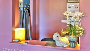 Un'area reception con uno specchio, una lampada, un peluche e un vaso con fiori.