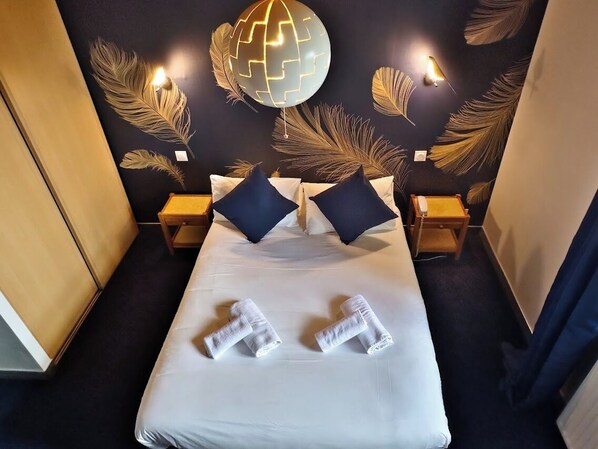 A hotel room with a large bed, two nightstands, and decorative wall art. - Le Prieuré (Locronan)