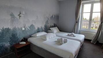 A hotel room with two beds, a bedside table, and a window with curtains.