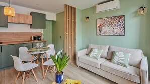 Un salon moderne avec un canapé, une table à manger et des chaises, une machine à café et une plante en pot.