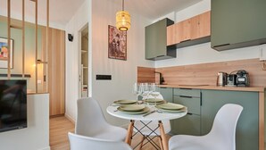 Une cuisine moderne avec des meubles en bois, une table à manger pour quatre personnes et un luminaire suspendu.