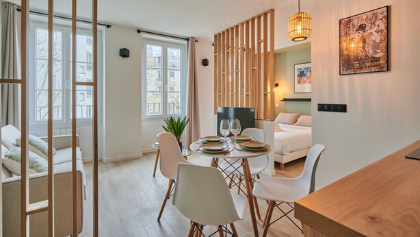 Une chambre d’hôtel moderne dotée d’un coin repas, d’un lit et d’une grande fenêtre.