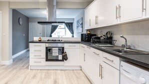 Une cuisine moderne avec des meubles blancs, un four encastré, un lave-vaisselle et un lave-linge.