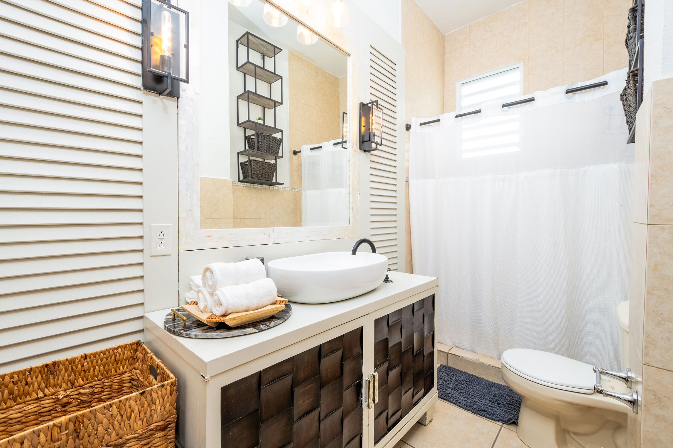 Een moderne badkamer met een witte wastafel, een donker houten kast en een douchegordijn.